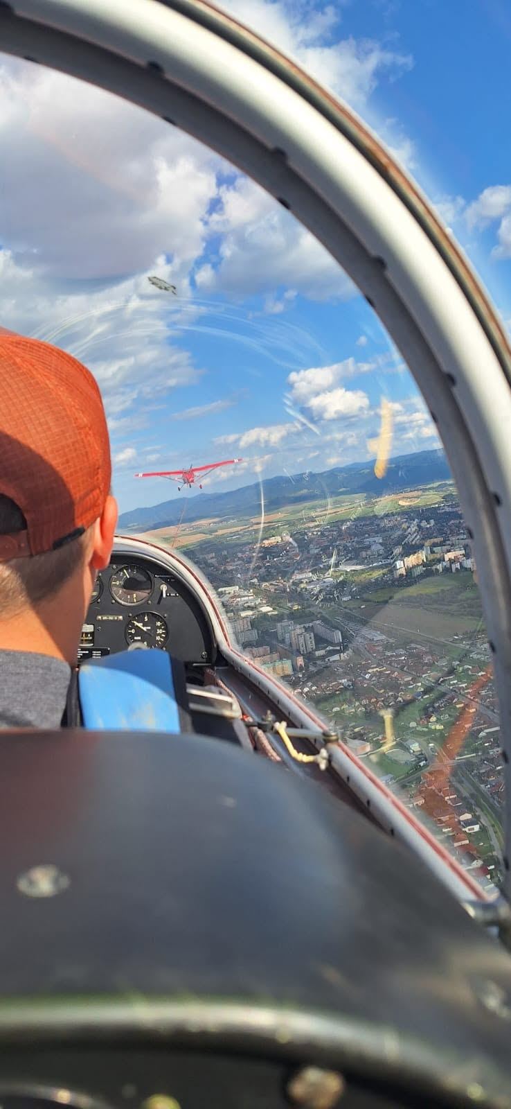 View from a glider on aerotow behind a red tug aircraft over a town
