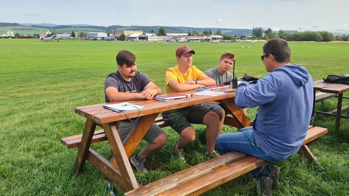 An instructor and students at a pre-flight briefing around a table on the airfield