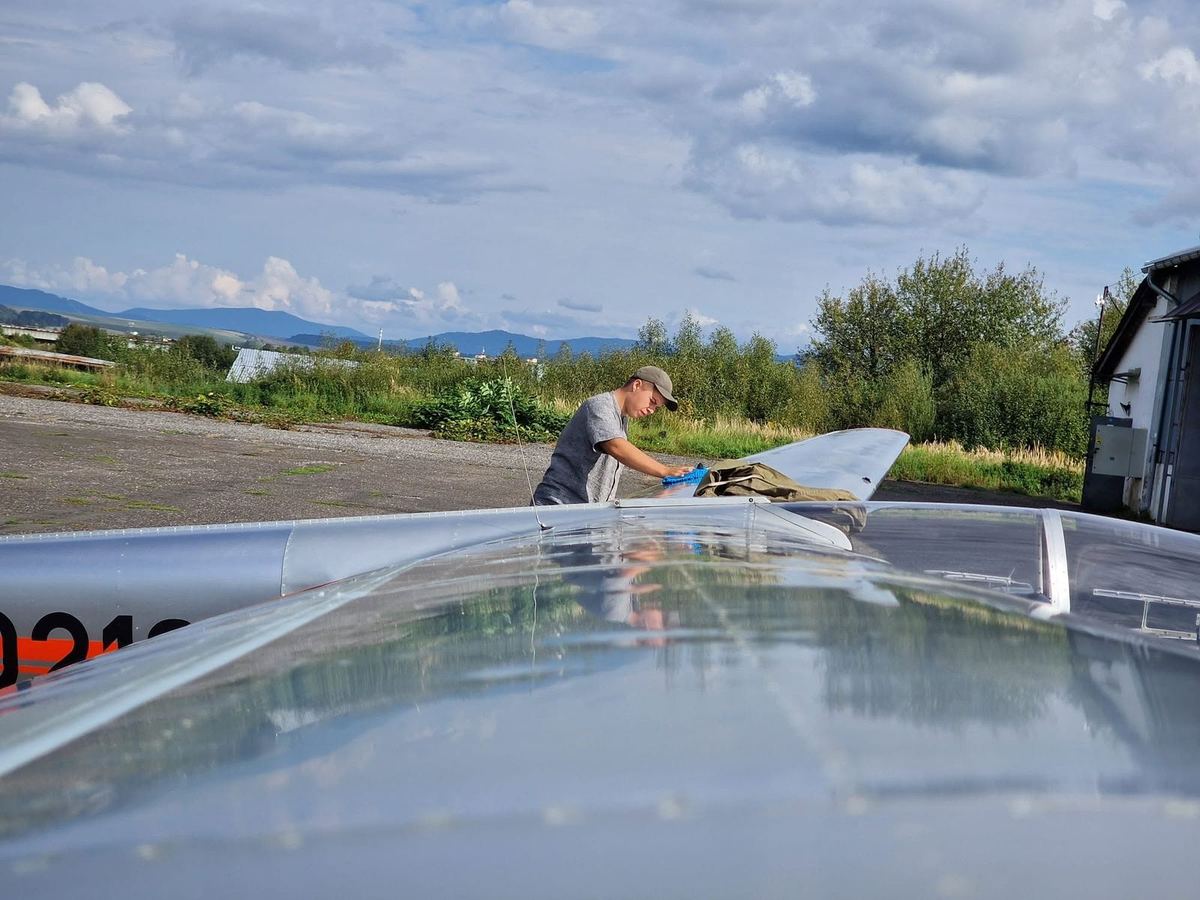 A student cleaning a glider wing after flying