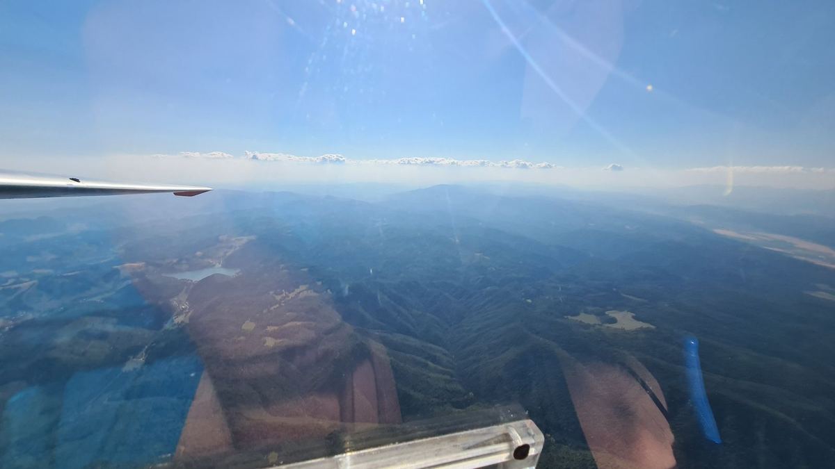 Forested ridges beneath a glider wing
