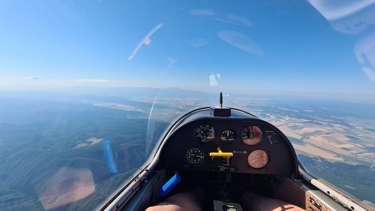 Glider cockpit above forests, with the High Tatras on the horizon