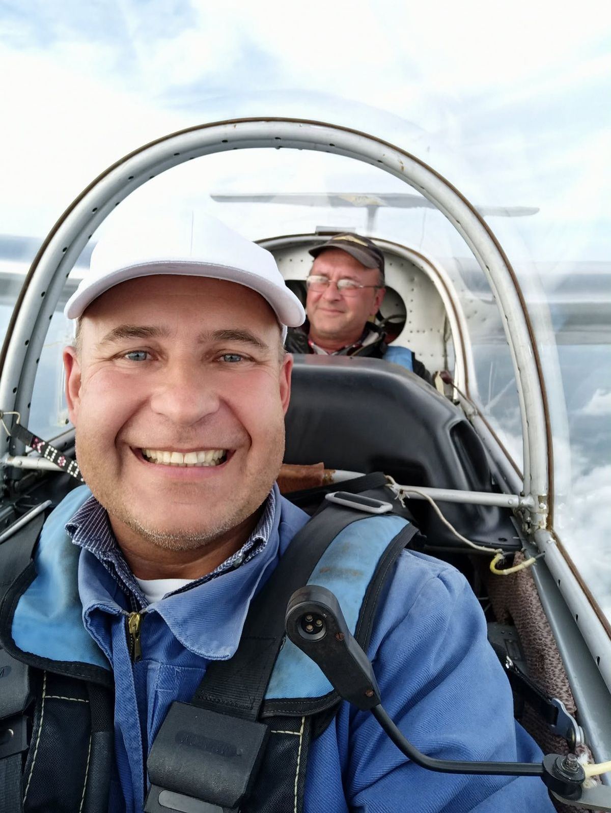 A smiling pilot and instructor in a glider cockpit in flight