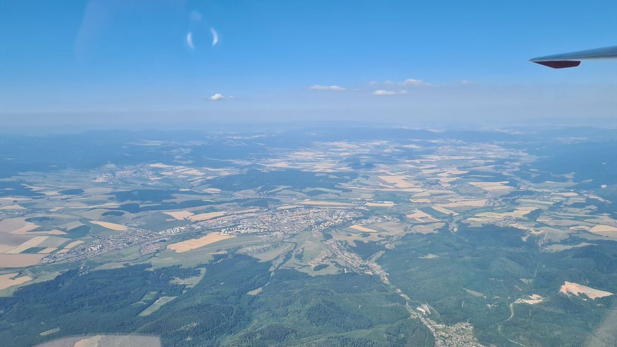 A town in a basin between fields and forests, seen from the air